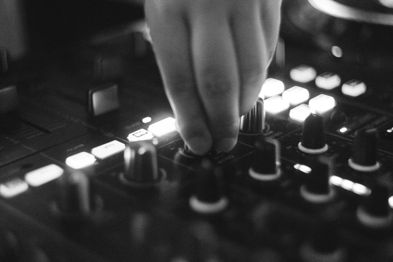 Close on LP's hands working a DJ mixer, buttons lit up