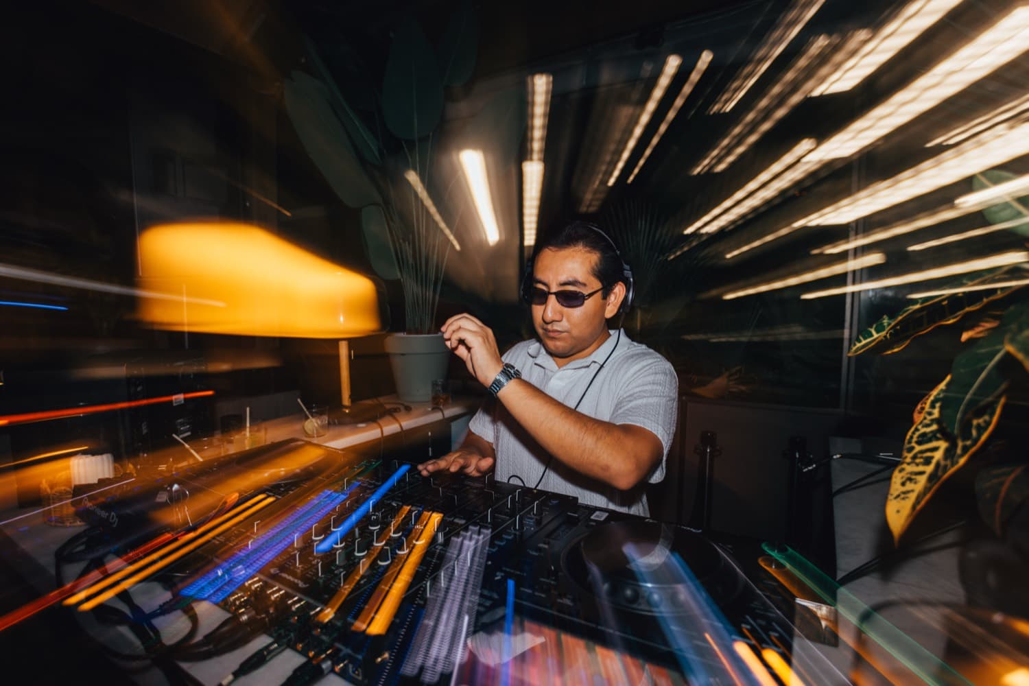 LP DJing with headphones on, colorful light trails streaking across the frame
