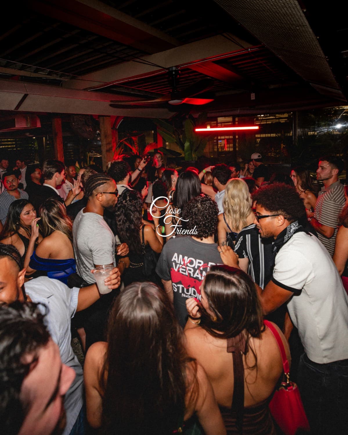 A packed dance floor under red light, mid-set