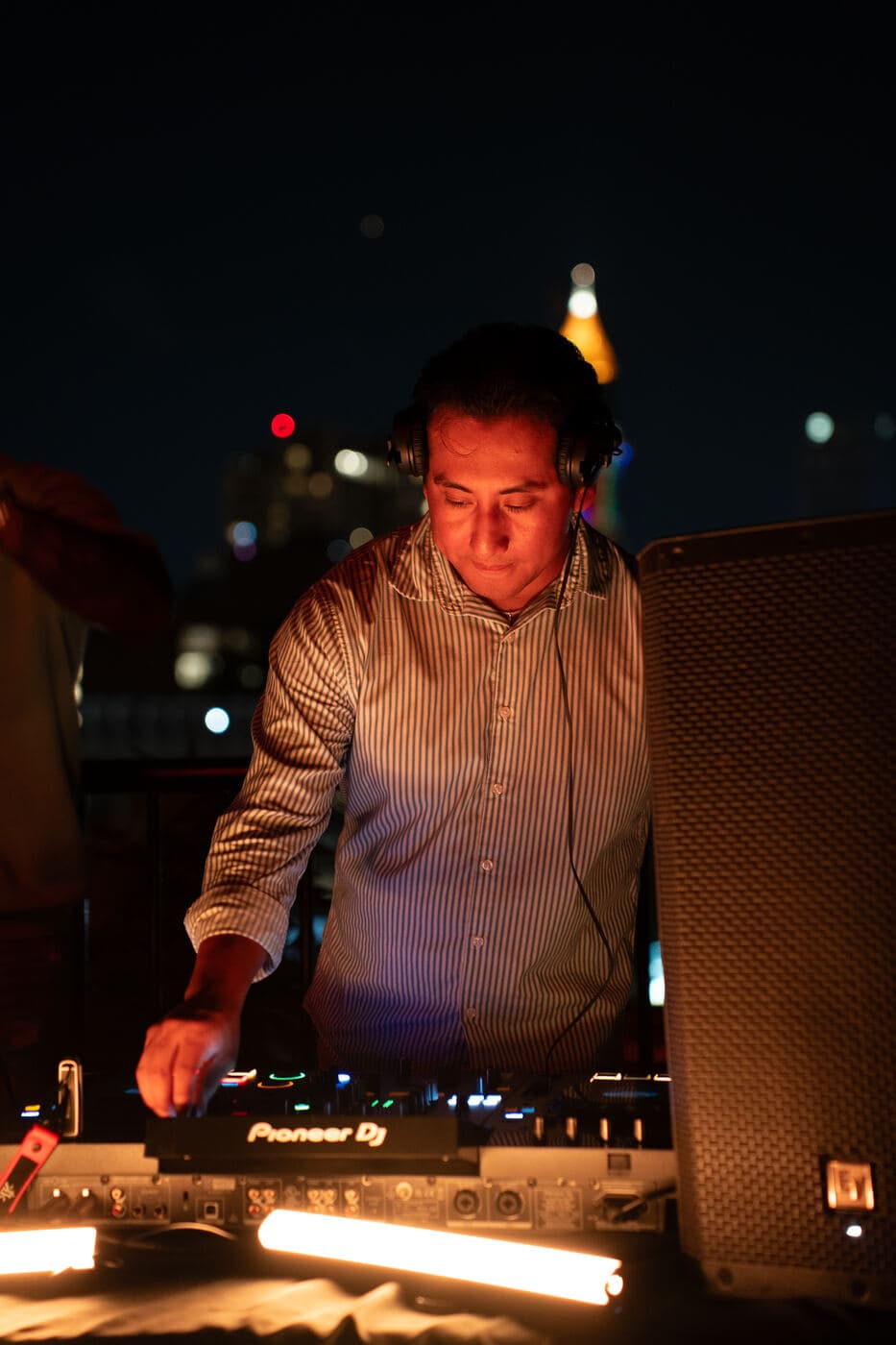 LP DJing on a rooftop with the Atlanta skyline lit up behind him